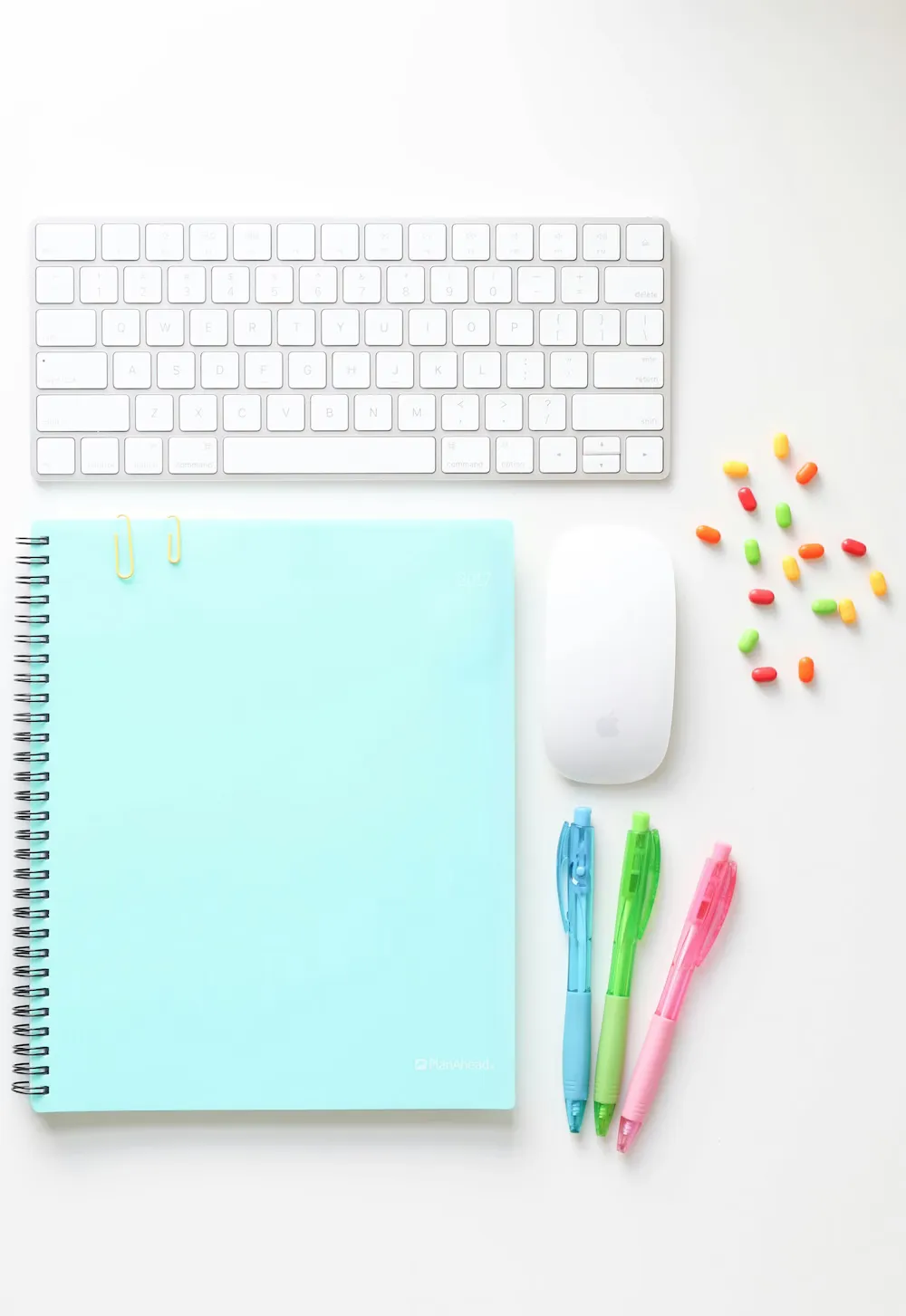 A notebook, laptop, and pens laid out together in a bright and inviting setting